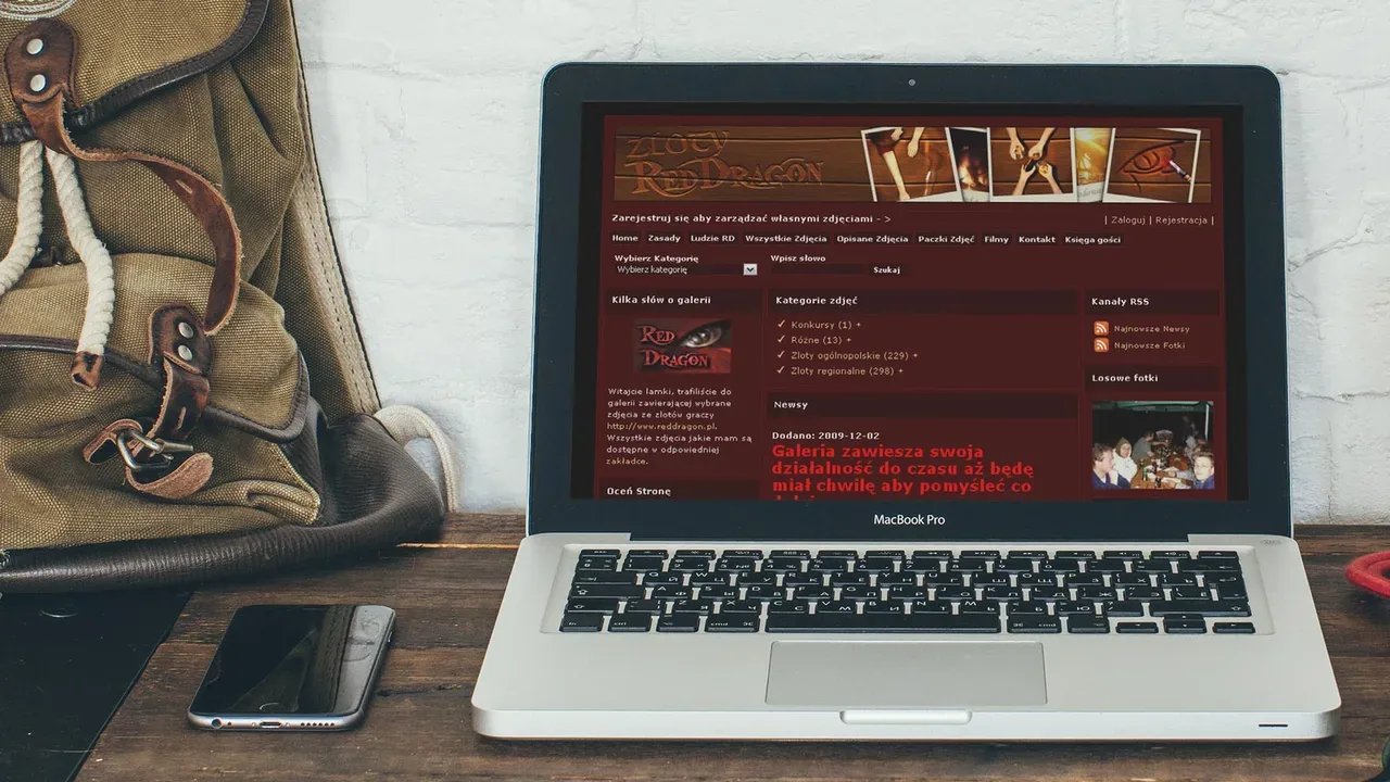Strona galerii fotograficznej RedDragon na MacBooku Pro na biurku