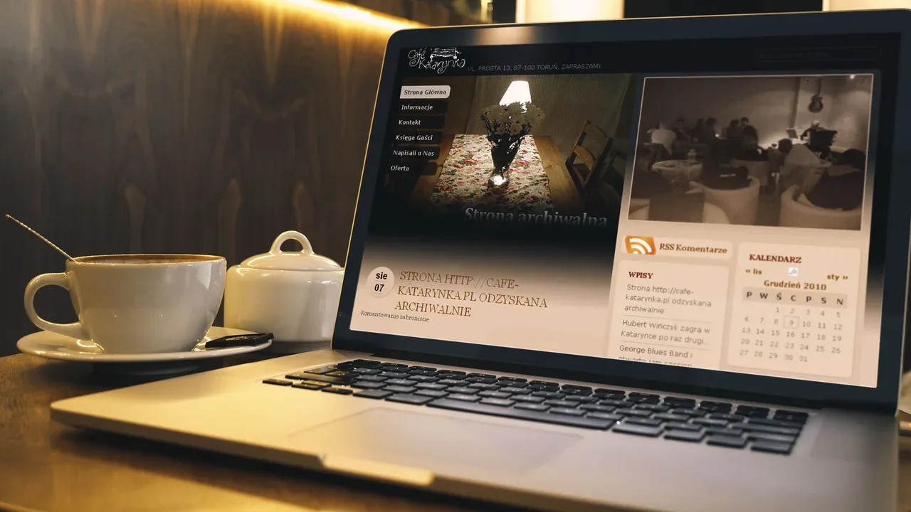Café Katarynka website on laptop in warm coffee shop setting